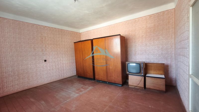 A room in a family house with wallpaper, wardrobes, and an old television.