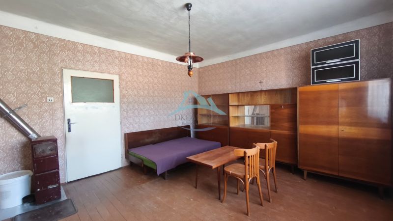 A room in a family house with wooden furniture, a bed, a table, and a stove.
