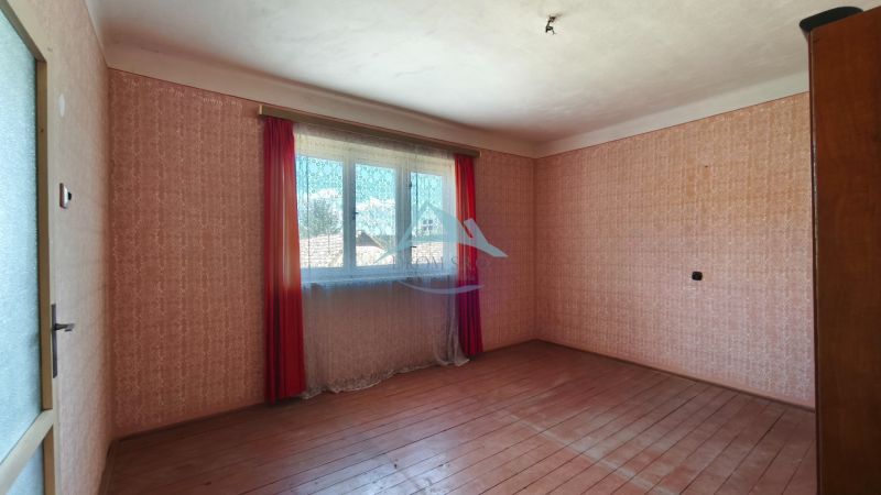 A room with patterned wallpaper and a wooden decor floor in a family house.