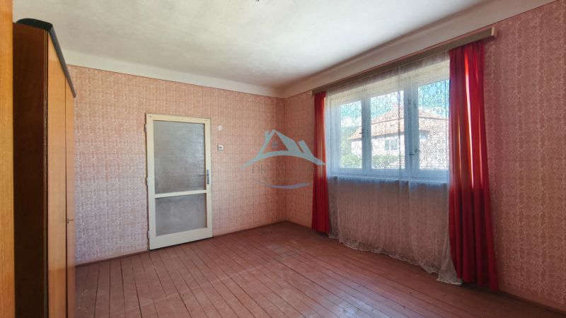 An empty room in a family house with a floor and patterned wallpaper.