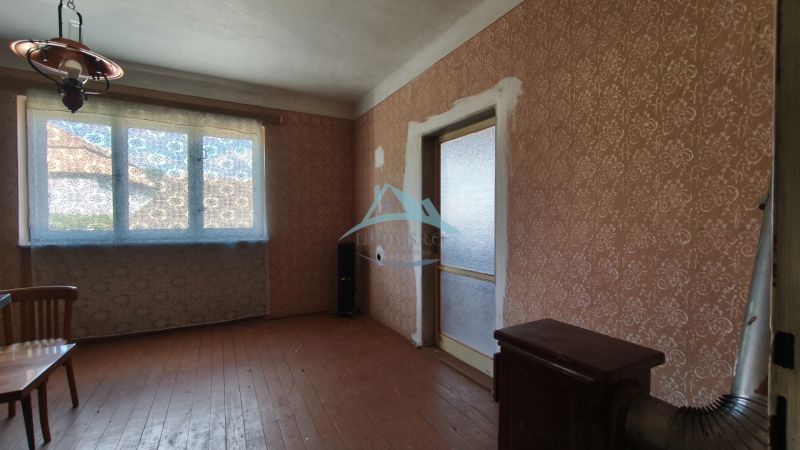 Interior of a family house with brown wallpaper and wood-patterned flooring.