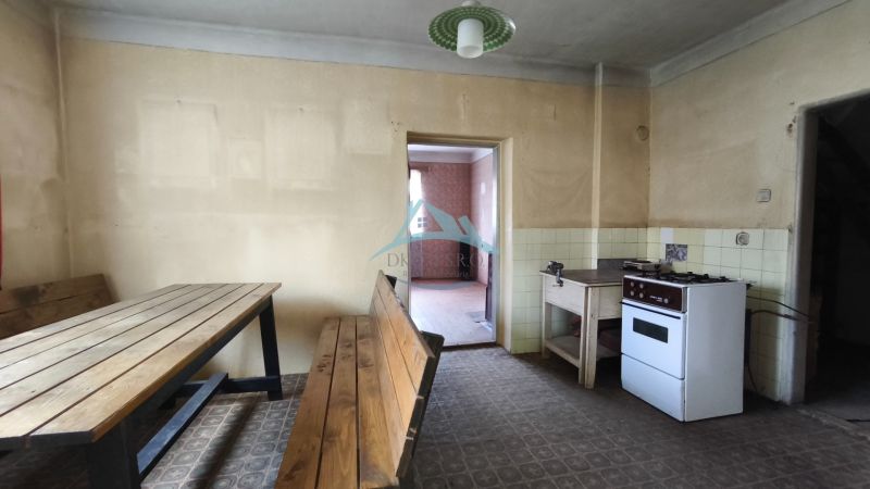 A kitchen in a family house with a dining table, a gas stove, and tiled flooring.
