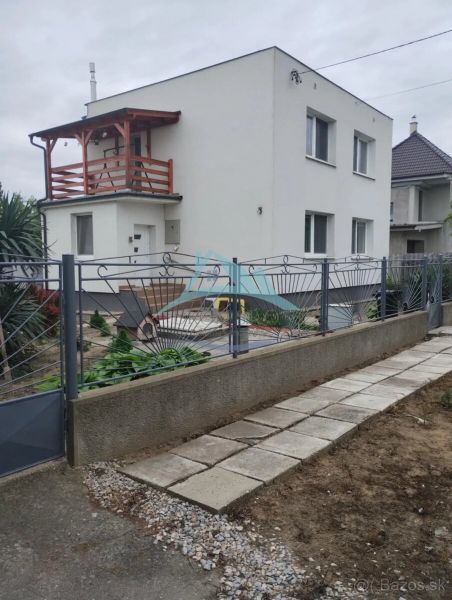 A family house in the city of Trnava with a white facade and a wooden balcony.