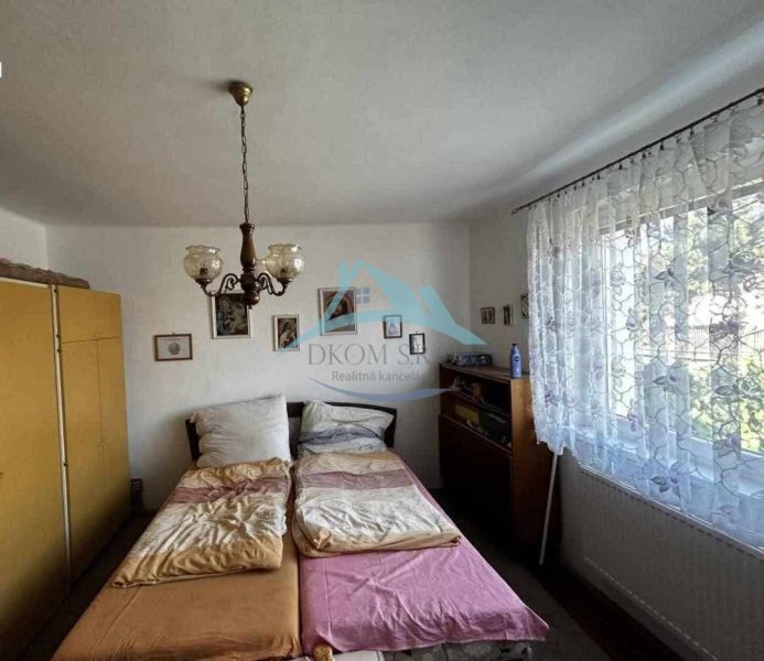 Bedroom with a double bed, chandelier, and curtains in a family house.