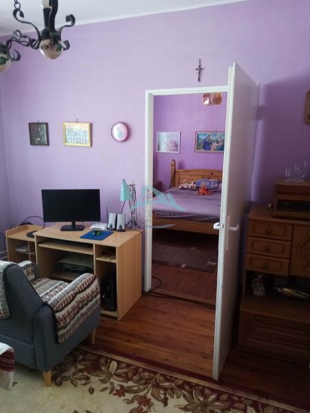 Living room in a family house with purple walls and a wooden-patterned floor.