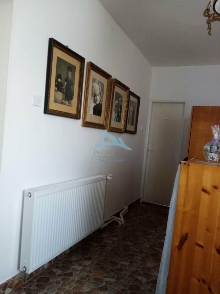 A hallway in a family house with photographs and a radiator, tiled floor.