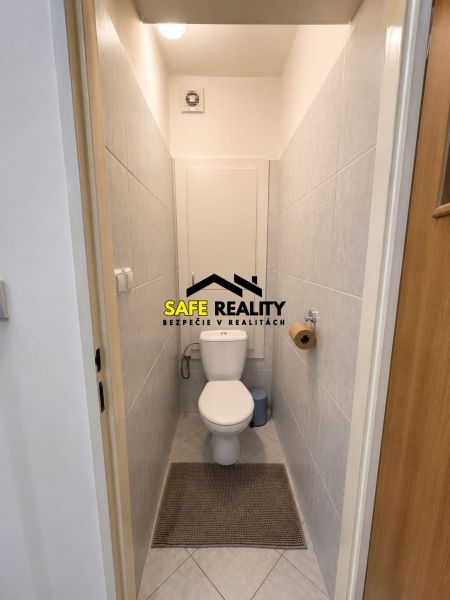A toilet with tiles in a 3-room apartment, light tiles, white sanitary ware.
