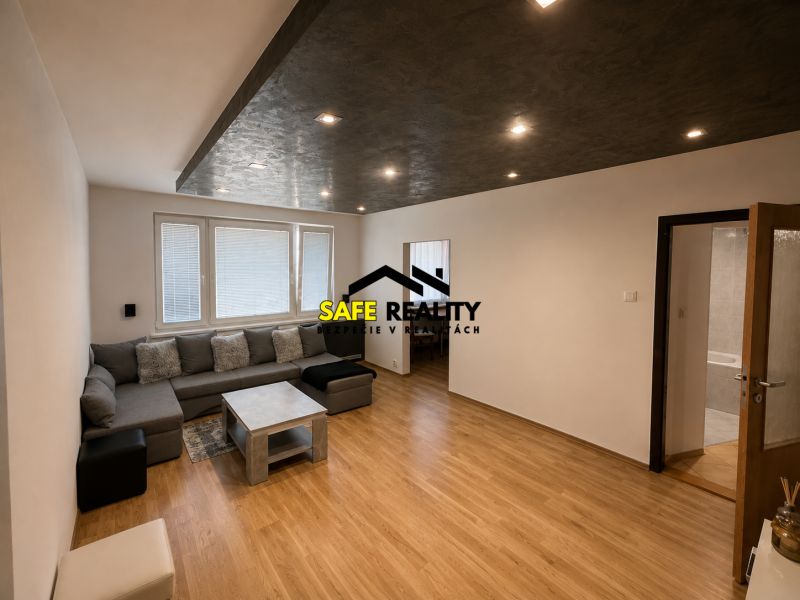 Living room in a three-room apartment with a wooden decor floor and seating.