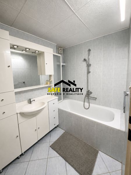 A bathroom in a 3-room apartment with a corner bathtub and white sink furniture.