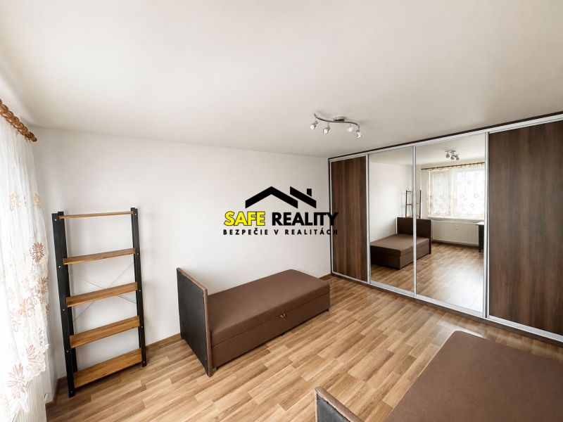 A bedroom in a 3-room apartment with a wooden decor floor, a mirrored wardrobe, and sofas.