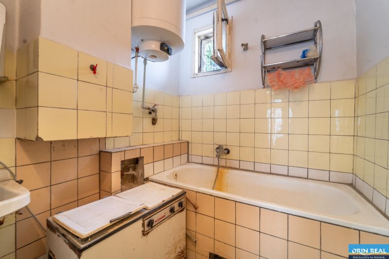 A bathroom in a family house with tiles and a bathtub, equipped with an old boiler.