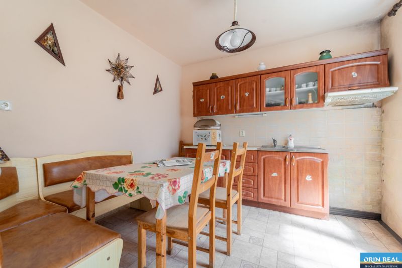 A kitchen in a family house with a table, chairs, kitchen unit, and decorative elements on the wall.