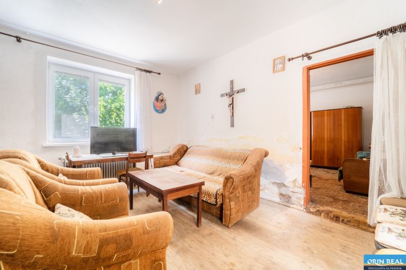 Living room in a family house with older sofas, a television, and a wooden decor floor.