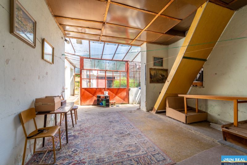 A family house with glass doors, a chair, a table, and a carpet on a floor with a wooden decor.
