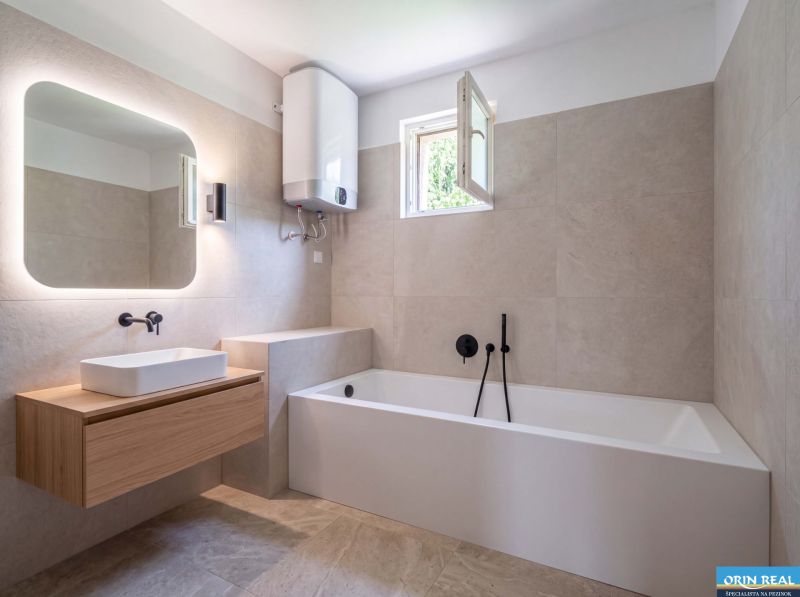 Bathroom with a bathtub and a sink in a family house with a wooden decor floor.