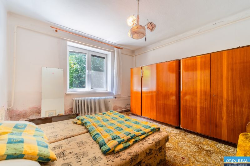 Bedroom in a family house with beds, a wooden wardrobe, and a radiator by the window.