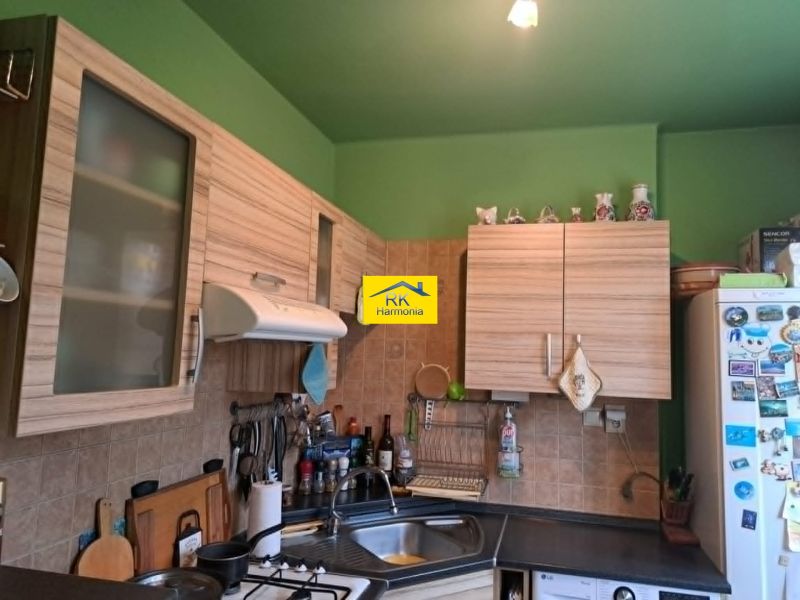 A kitchen in a 2-room apartment with wooden cabinets and a green wall.