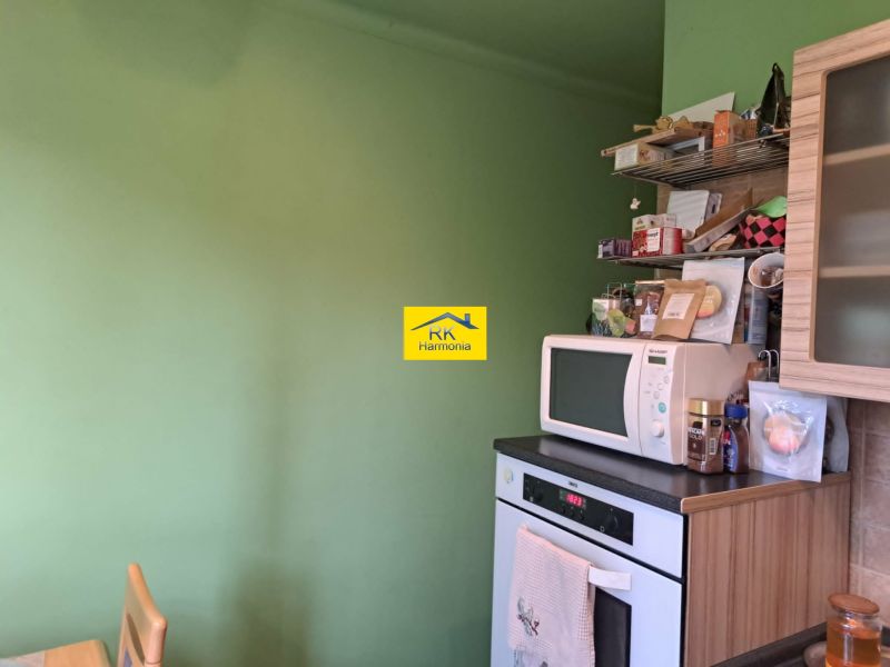 A kitchen in a 2-room apartment with a microwave and open shelves.
