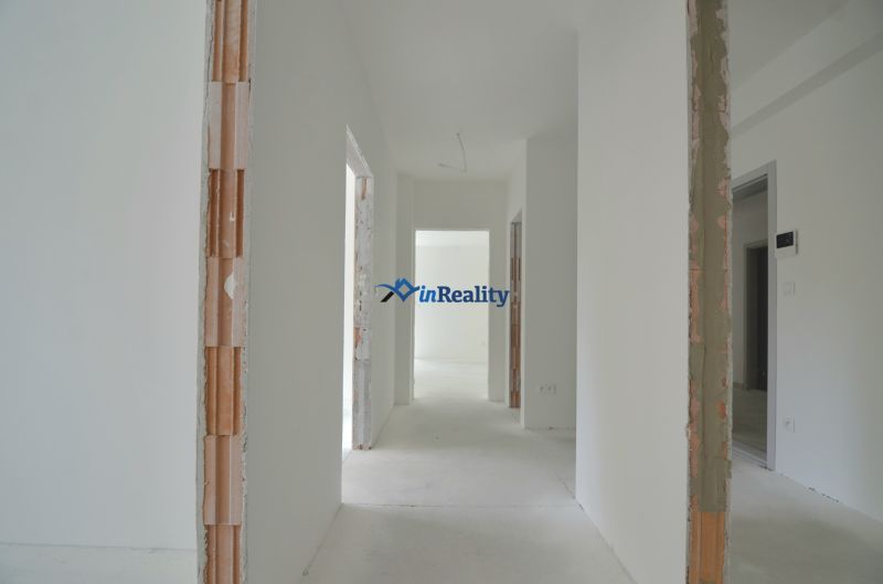 A bright hallway in a 3-room apartment with unfinished walls and a concrete floor.
