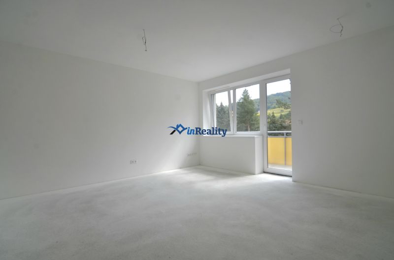 A bright room in a 3-room apartment with large windows and a balcony, overlooking greenery.