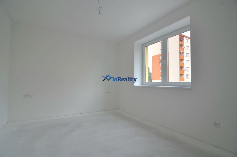 An empty room in a 3-room apartment with white walls and a large window.
