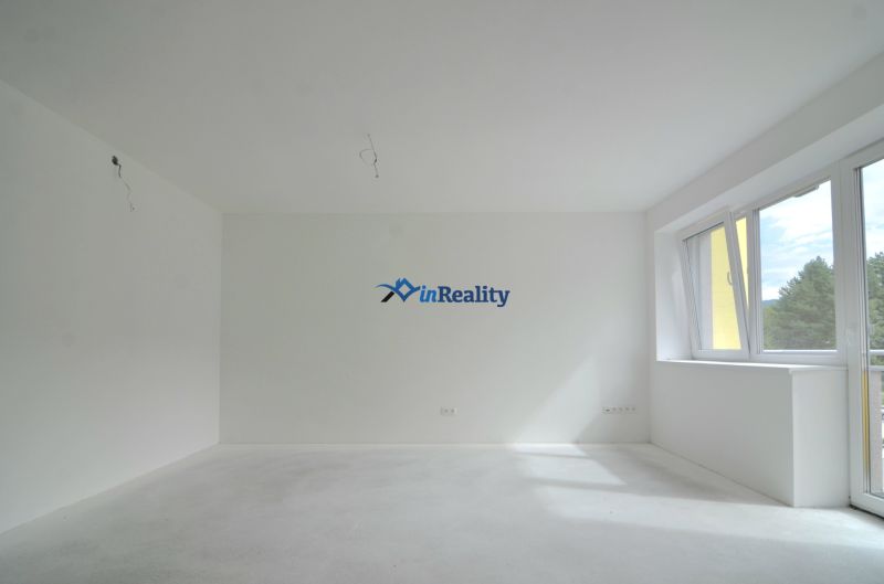 A bright room in a 3-room apartment with a large window and white walls.