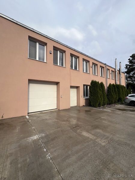 Warehouses and halls in Veľký Šariš with a concrete access road and garage doors.
