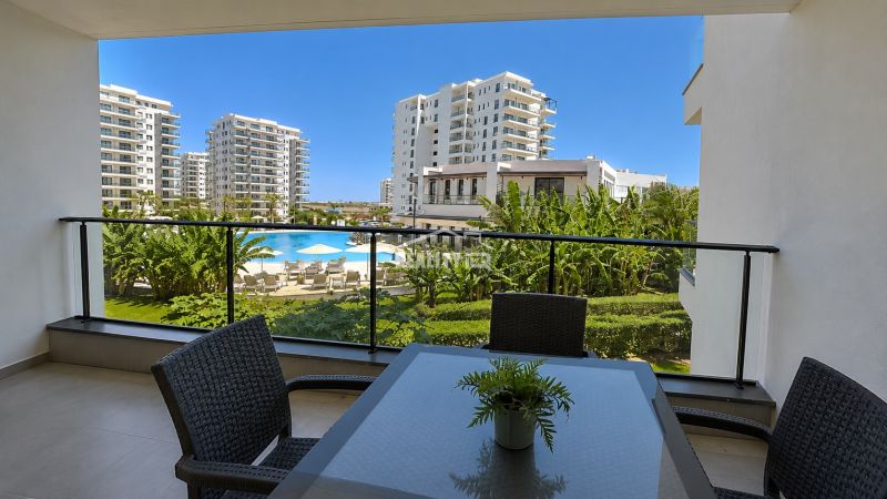 The balcony of a studio apartment in Bogazi with a view of the pool and apartment buildings.