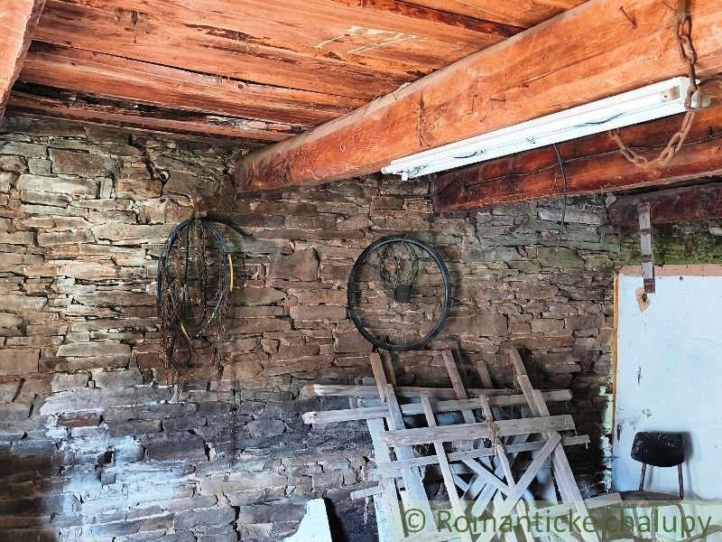 Stone wall in a space with a wooden beam and stored items. Real estate - housing.