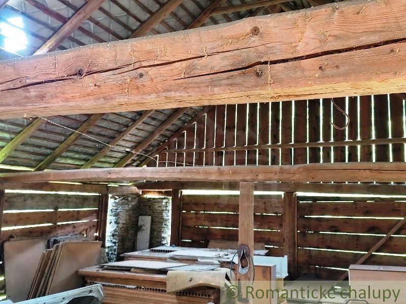 The interior of a wooden barn with thick beams and stored materials. Land - housing.