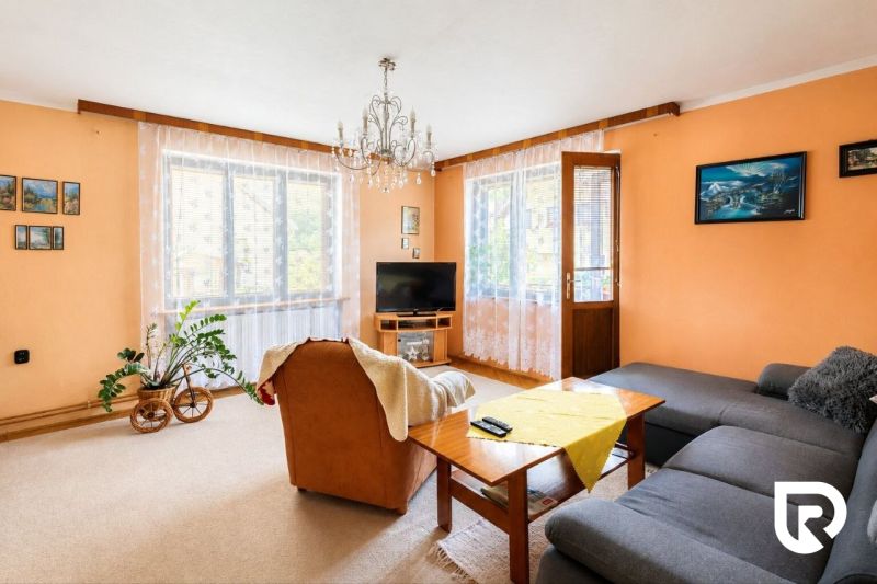 Living room with cream walls, an orange armchair, and a gray sofa in a family house.