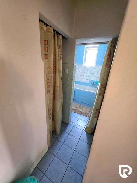 Bathroom in a family house with a blue bathtub and curtains, tiles on the floor.