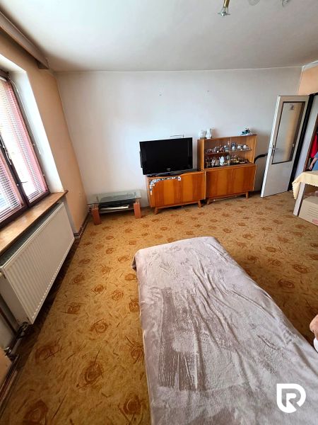Living room in a family house with a television, display cabinets, and a decorative carpet.