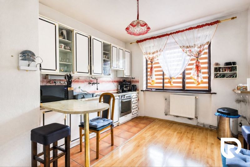 A kitchen in a family house with tiles and a wooden decor floor.
