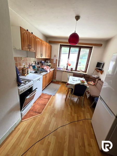 A kitchen with wooden decor, a gas stove, a refrigerator, and a dining table in a family house.