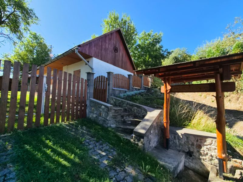 A family house in Mikušovce with a wooden fence and a stone staircase.