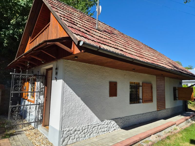 A family house in Mikušovce with wooden shutters and a red roof surrounded by greenery.