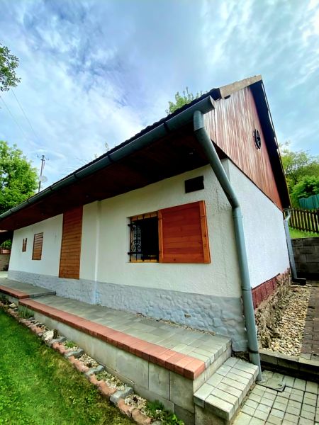 A family house in Mikušovce with a roof covering, wooden shutters, and a well-maintained garden.