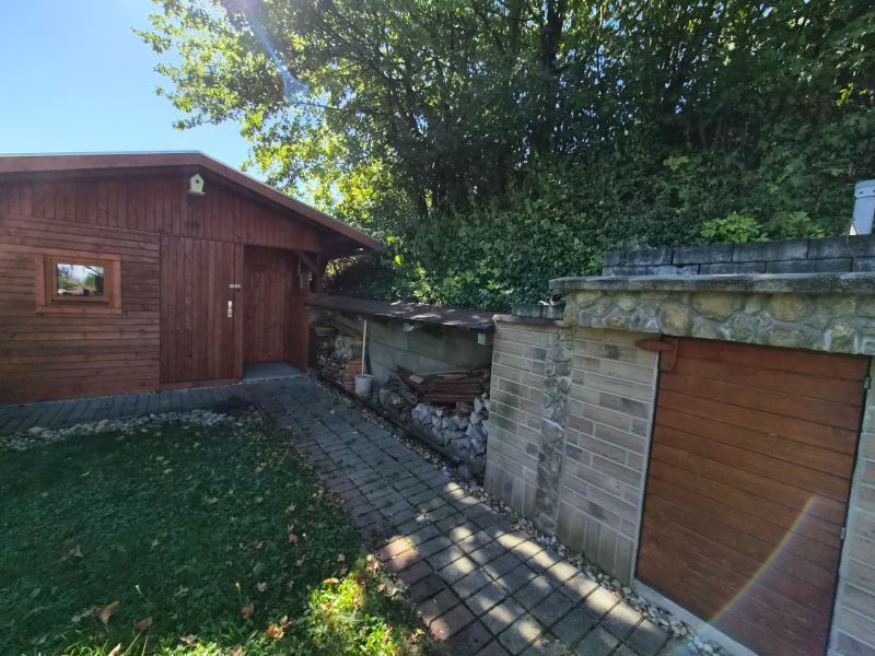 A wooden shelter and a stone building in the garden of a family house in Mikušovce.