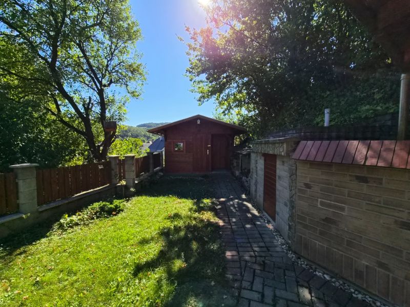 Garden at a family house in Mikušovce, outdoor seating, sunny day, stone pathway.