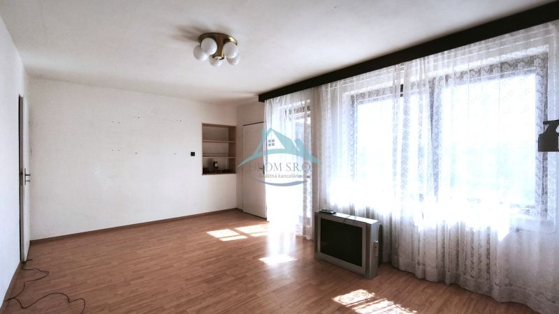 Living room in a family house with a wooden decor floor and large windows with curtains.