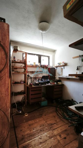 Workshop with shelves and a wooden table in a family house, floor with wooden decor.