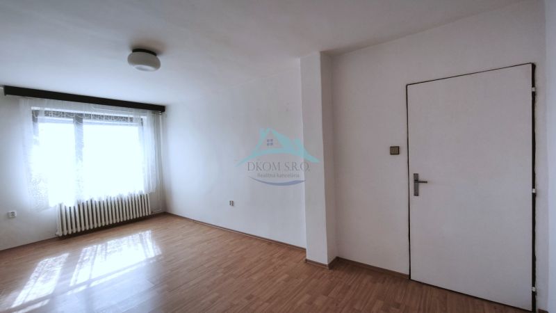 A spacious room in a family house with a wood-decorated floor and a large window.