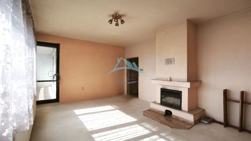 Interior of a family house with a fireplace and large windows with white curtains.