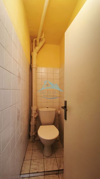 A small, narrow toilet with tiles in a family house with white tiles.