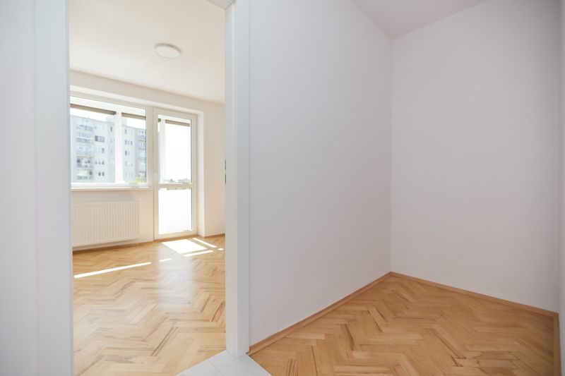A bright room in a 3-room apartment with a wood-patterned floor and a large window.