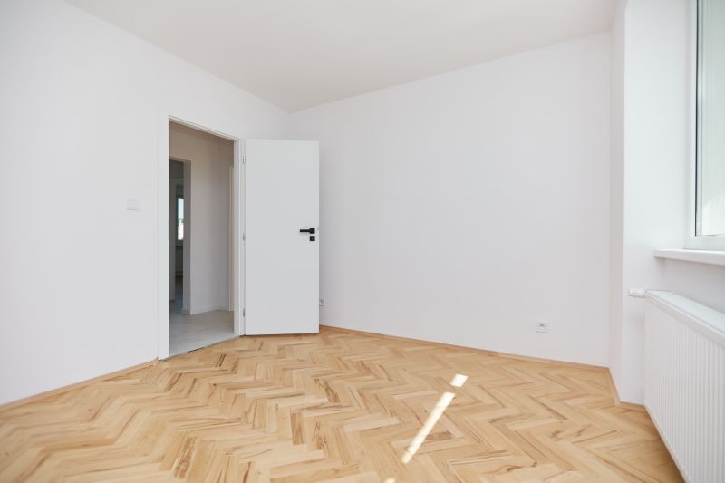 A room with white walls and a wooden decor floor in a 3-room apartment.