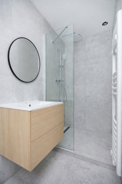 Bathroom in a 3-room apartment with a modern shower and wooden decor on the cabinet.