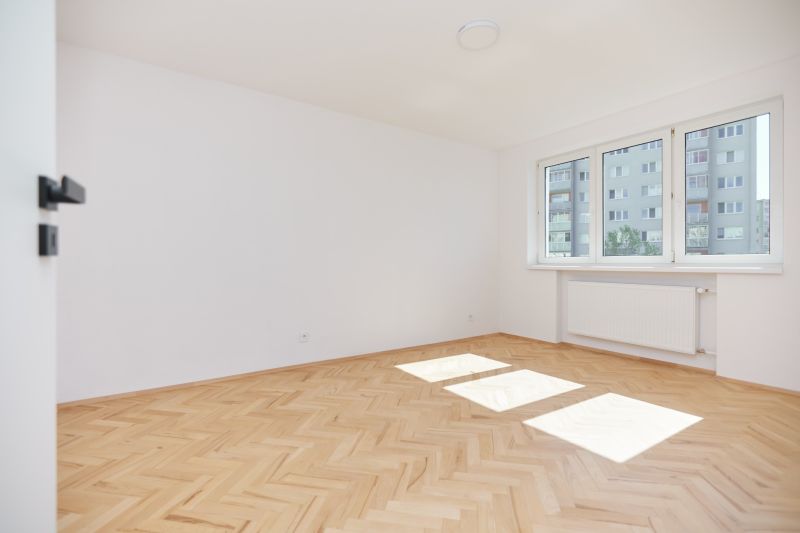 A bright room with white walls and a floor with a wood decor in a 3-room apartment.