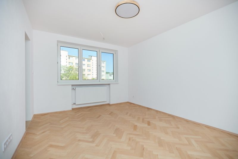 A room in a 3-room apartment with white walls and a floor with a wood decor.